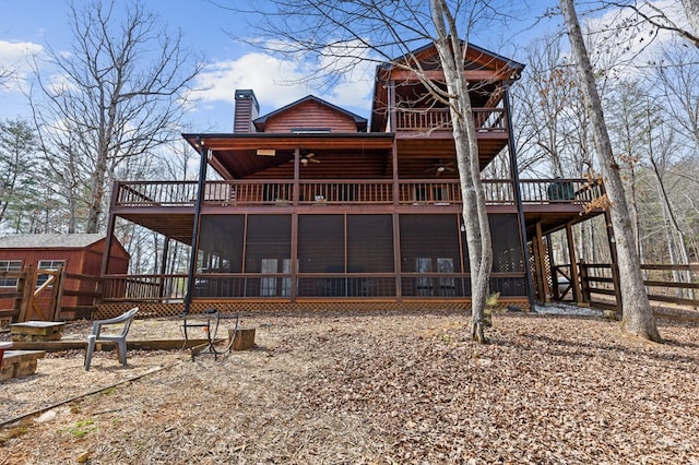 rear view of house with ceiling fan, a deck, an outdoor structure, and faux log siding