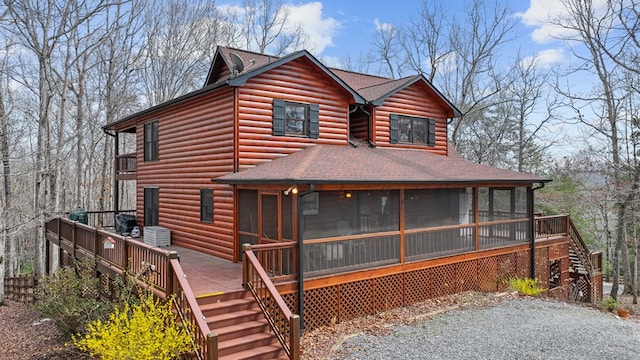 back of property featuring stairway, a shingled roof, log veneer siding, and a sunroom