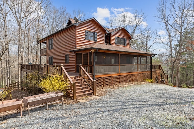 view of front facade with log veneer siding, stairs, and a sunroom