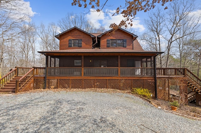 chalet / cabin with roof with shingles, faux log siding, stairs, and a sunroom