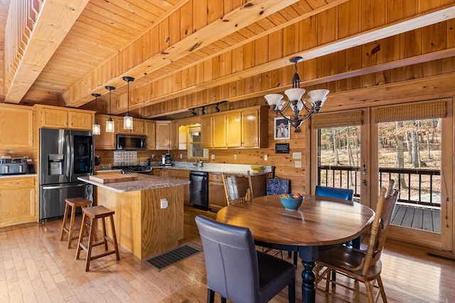 dining area featuring visible vents, light wood-style flooring, wood ceiling, wood walls, and beamed ceiling