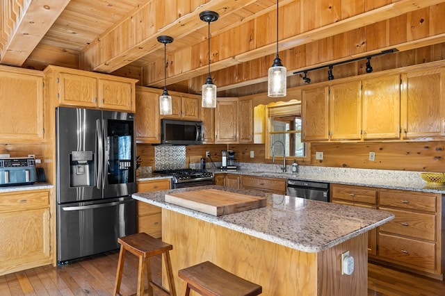 kitchen with a kitchen island, beamed ceiling, hardwood / wood-style flooring, stainless steel appliances, and a sink