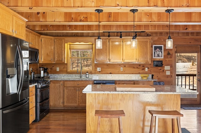 kitchen featuring a sink, a kitchen bar, appliances with stainless steel finishes, and dark wood finished floors