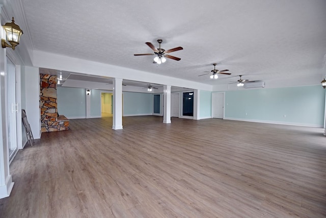 unfurnished living room featuring a wall mounted AC, a textured ceiling, and hardwood / wood-style flooring