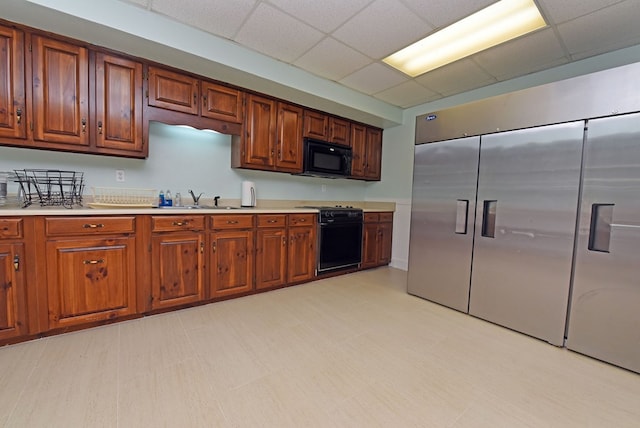 kitchen featuring a drop ceiling, black appliances, and sink