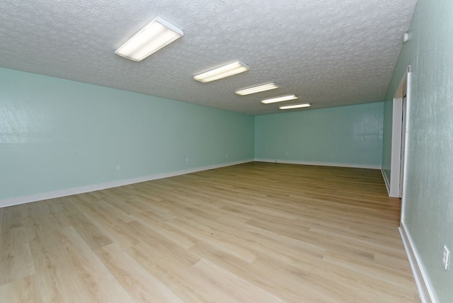 spare room with light hardwood / wood-style floors and a textured ceiling