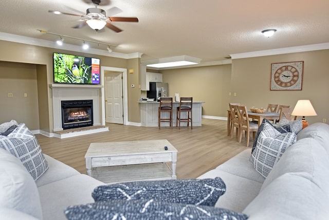 living room with track lighting, a textured ceiling, ceiling fan, crown molding, and hardwood / wood-style flooring