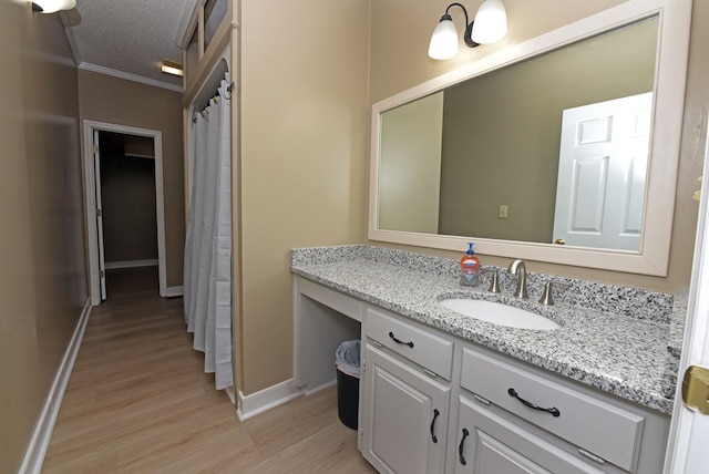 bathroom featuring vanity, a textured ceiling, hardwood / wood-style flooring, and crown molding