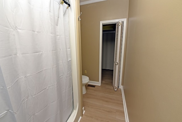 bathroom with curtained shower, toilet, and hardwood / wood-style flooring