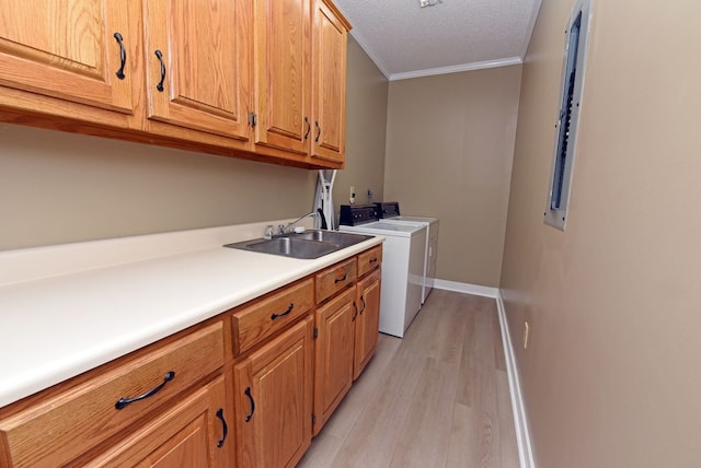 clothes washing area with washing machine and clothes dryer, sink, cabinets, light hardwood / wood-style flooring, and ornamental molding