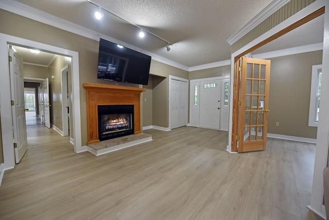 unfurnished living room featuring french doors, rail lighting, crown molding, light wood-type flooring, and a textured ceiling