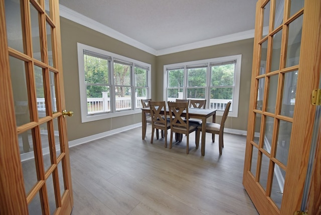 dining area with french doors, light wood-type flooring, a textured ceiling, and ornamental molding