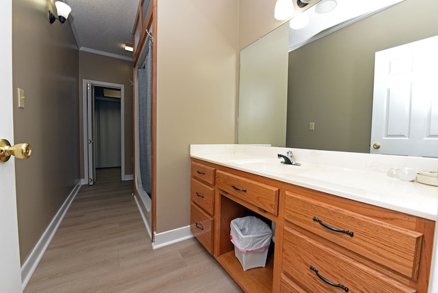 bathroom with crown molding, hardwood / wood-style floors, vanity, and a textured ceiling