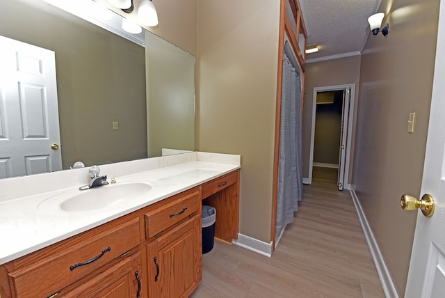 bathroom with vanity, crown molding, wood-type flooring, and a textured ceiling