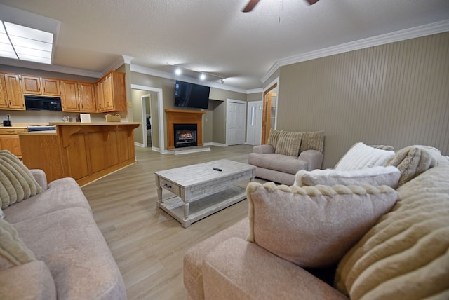 living room featuring ceiling fan, light hardwood / wood-style flooring, a textured ceiling, and ornamental molding