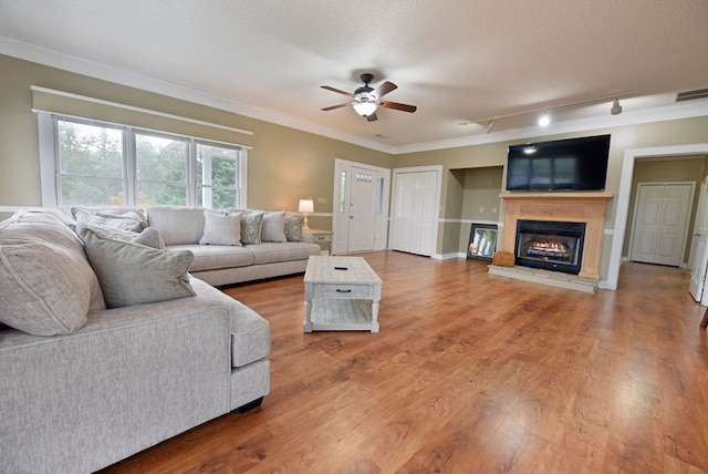 living room featuring ceiling fan, ornamental molding, track lighting, a textured ceiling, and hardwood / wood-style flooring