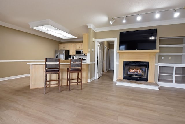 kitchen featuring light brown cabinets, stainless steel appliances, light hardwood / wood-style flooring, a textured ceiling, and a breakfast bar area