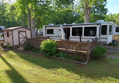 back of house with a lawn, a wooden deck, and a storage shed