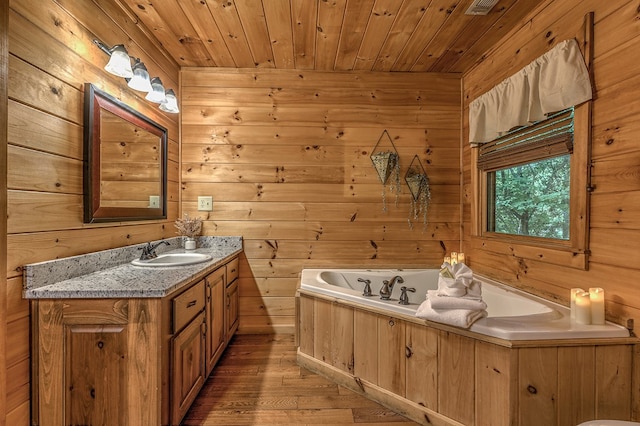 bathroom featuring a bath, hardwood / wood-style floors, wooden walls, vanity, and wood ceiling