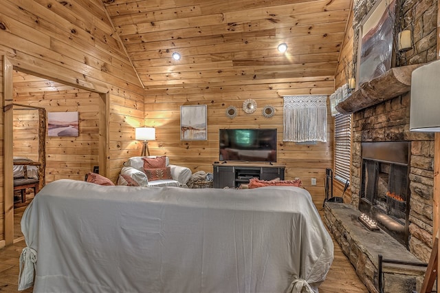 living room featuring wooden ceiling, wood walls, light hardwood / wood-style floors, vaulted ceiling, and a fireplace