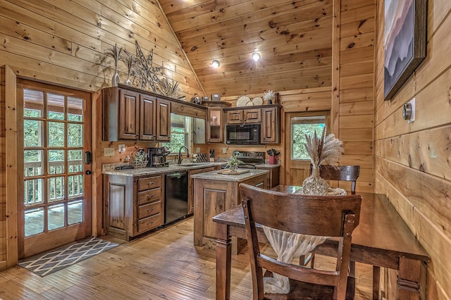 kitchen with a kitchen island, plenty of natural light, wooden walls, and black appliances