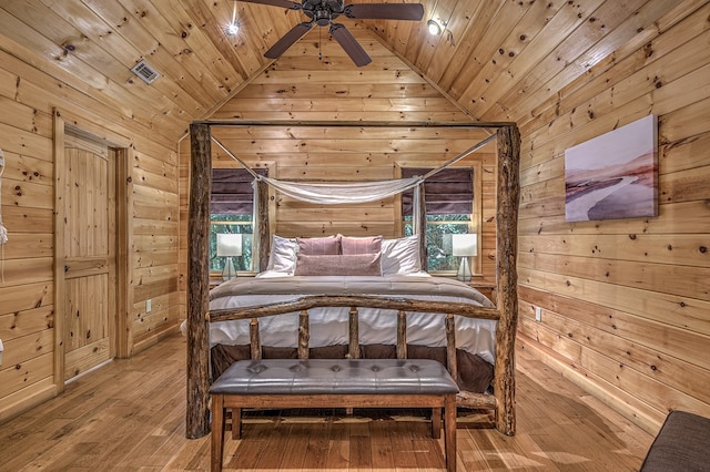 bedroom with wood walls, lofted ceiling, and hardwood / wood-style flooring