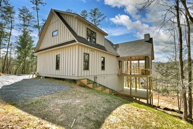 back of house featuring roof with shingles and board and batten siding