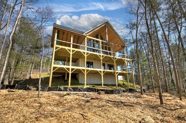 rear view of property featuring board and batten siding and a wooden deck