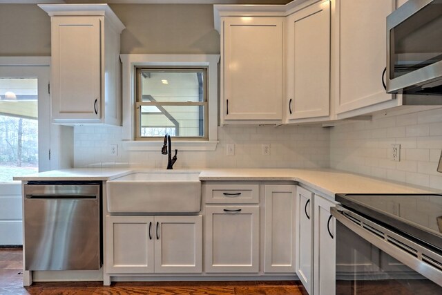 kitchen featuring white cabinetry, sink, dark wood-type flooring, stainless steel appliances, and backsplash