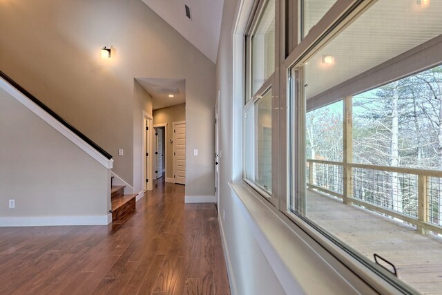 unfurnished living room featuring high vaulted ceiling and dark hardwood / wood-style floors