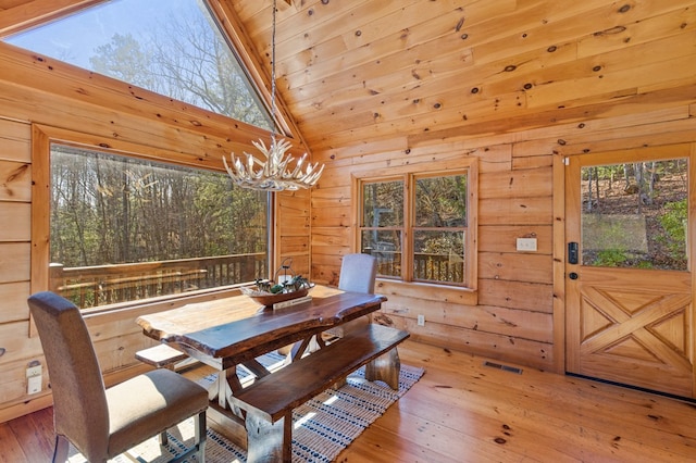 dining space featuring an inviting chandelier, wood walls, and wood-type flooring