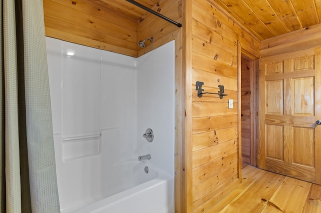 bathroom featuring hardwood / wood-style flooring, wooden walls, shower / tub combo with curtain, and wooden ceiling