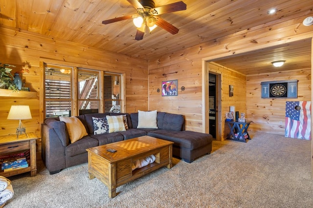 living area featuring wood walls, wooden ceiling, carpet flooring, and a ceiling fan