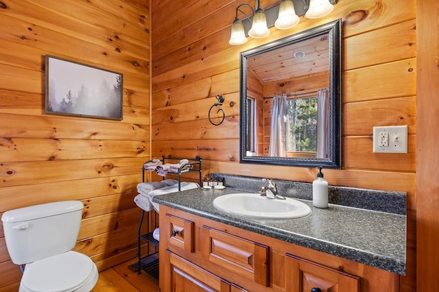 bathroom featuring vanity, toilet, and wooden walls