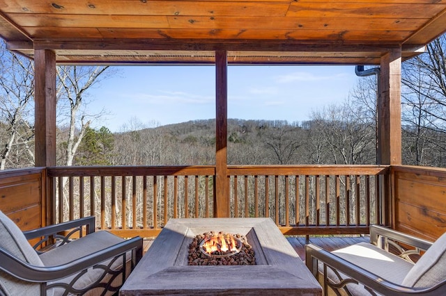 wooden terrace with a fire pit and a forest view