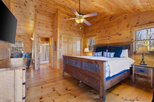 bedroom featuring multiple windows, wood walls, and light wood-type flooring