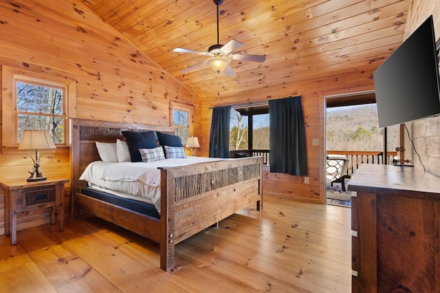 bedroom with lofted ceiling, access to outside, wood walls, and light wood-style flooring