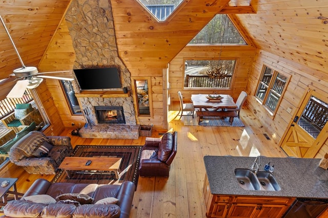 interior space with light wood-type flooring, a fireplace, high vaulted ceiling, and wooden walls