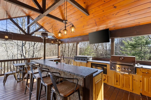 wooden deck with grilling area, outdoor dry bar, and exterior kitchen