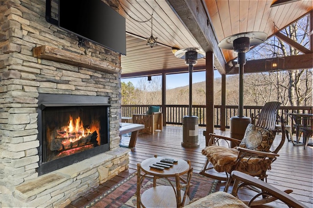 exterior space featuring wood ceiling, a wealth of natural light, an outdoor stone fireplace, and a mountain view