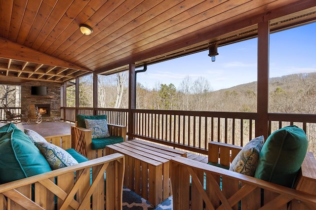 sunroom / solarium with wood ceiling, a fireplace, and a forest view