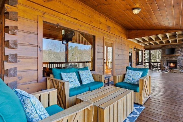 interior space with beamed ceiling, an outdoor stone fireplace, and wood ceiling