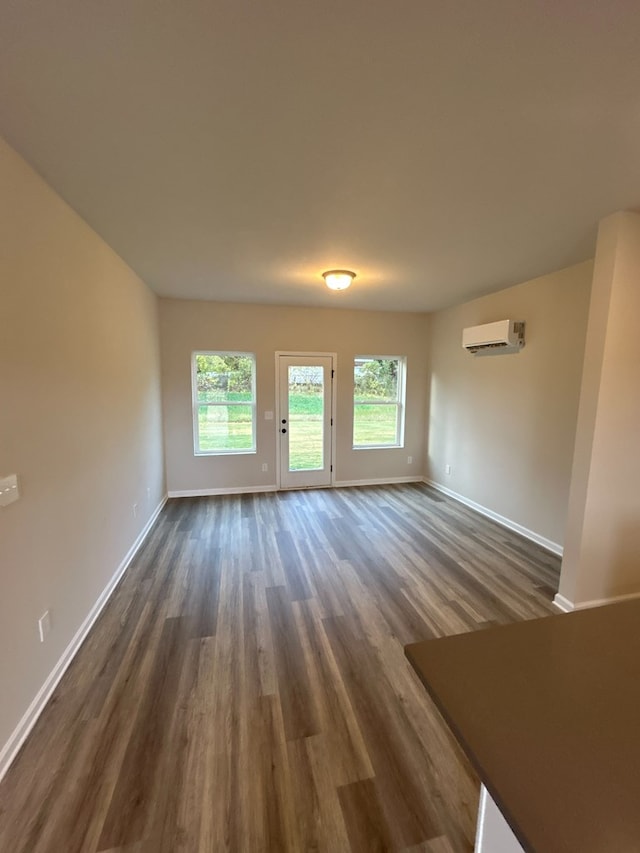 unfurnished room with dark hardwood / wood-style flooring and an AC wall unit