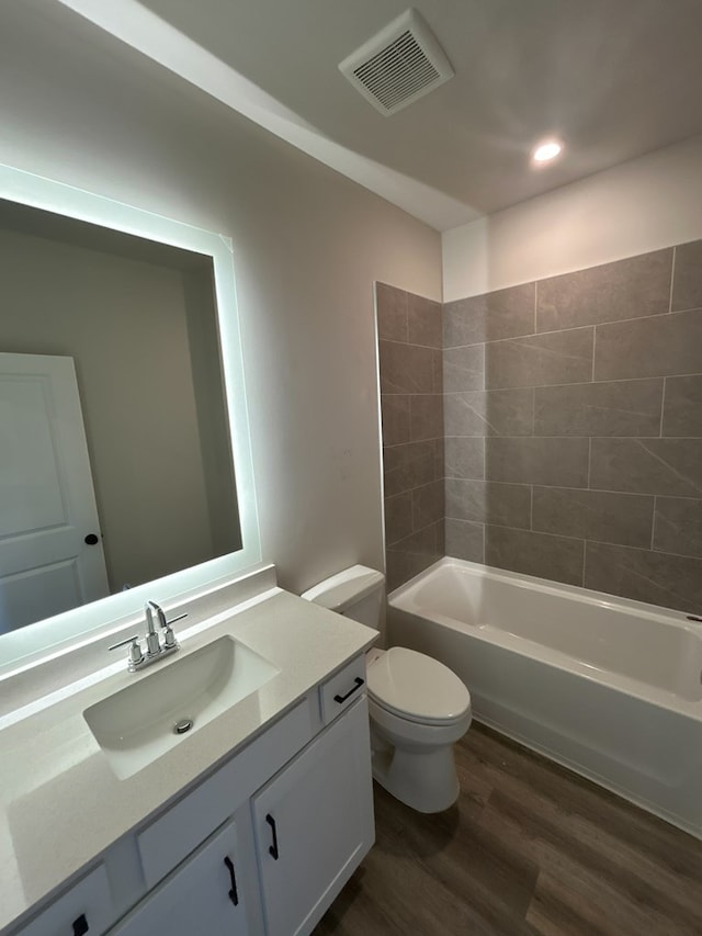 full bathroom with tiled shower / bath, hardwood / wood-style floors, vanity, and toilet