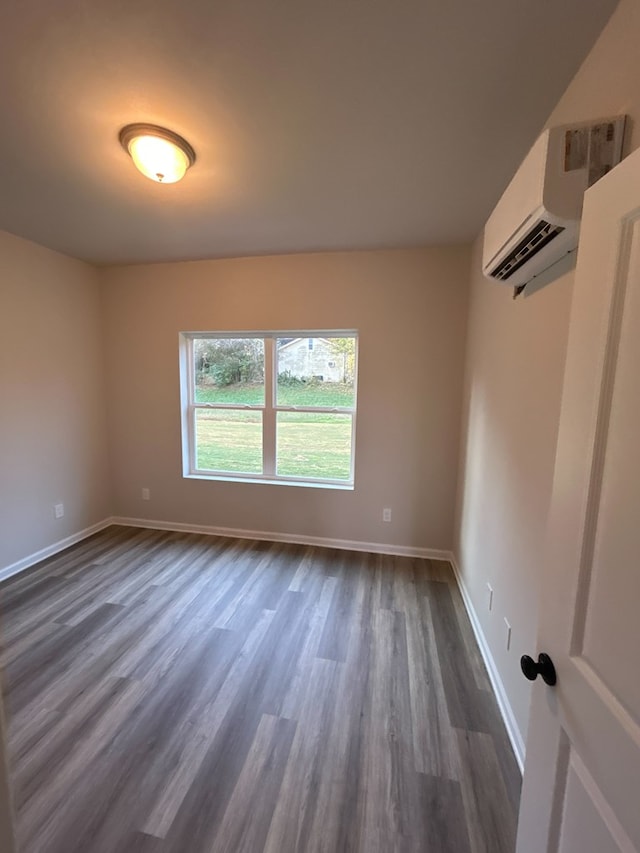 empty room featuring an AC wall unit and dark hardwood / wood-style floors