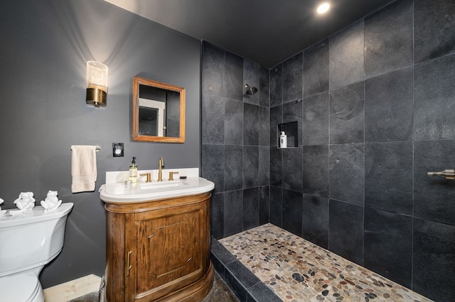 bathroom featuring toilet, tiled shower, and vanity