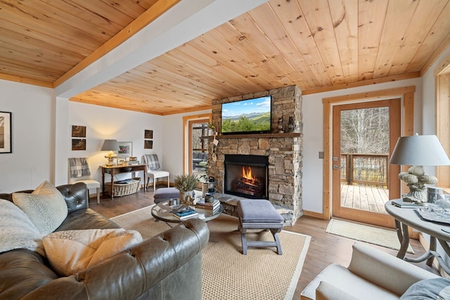 living room featuring a stone fireplace, hardwood / wood-style floors, and wooden ceiling