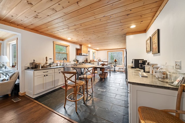 kitchen with white cabinets, dark wood-type flooring, sink, kitchen peninsula, and wooden ceiling