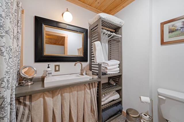 bathroom with wooden ceiling, sink, and toilet