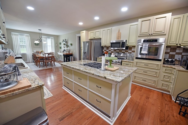 kitchen with decorative backsplash, pendant lighting, a center island, and appliances with stainless steel finishes